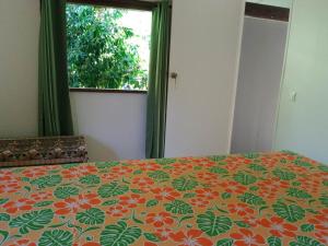 VaïareFare Mihimana的一间卧室配有一张带橙色和绿色床罩的床。