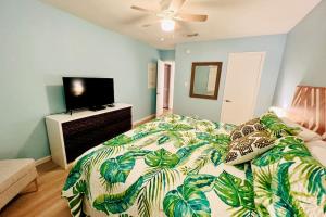 格尔夫海岸Large 2BR Across From Beach & 5 Min From Hangout的一间卧室配有一张带绿叶被子的床和一台电视机