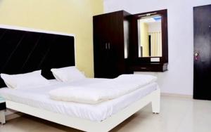 MundraHotel 7 Seas的一张白色的床,位于带镜子的房间里