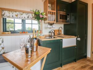 诺丁汉Poppie's Shepherds Hut的厨房配有绿色橱柜和木桌