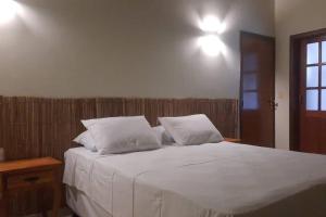 皮雷诺波利斯Casa Pequizeiro的一间卧室配有带白色床单和枕头的床。
