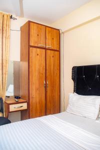 蒙巴萨The Nest Studio Apartment in Bamburi Mombasa的卧室配有木制橱柜,位于床边