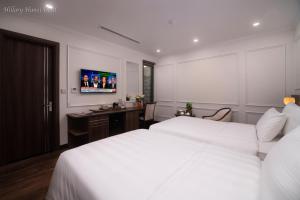 河内Hillary Hanoi Hotel的一间卧室配有两张床、一张桌子和一台电视。