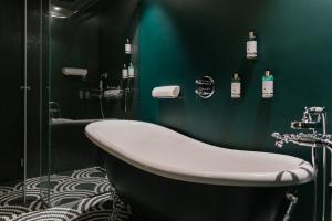 里斯本Art Legacy Hotel Baixa-Chiado的带浴缸和绿色墙壁的浴室