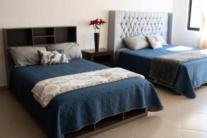 Santa GertrudisLa casita de la Bici的一间卧室配有两张蓝色床罩和花瓶。