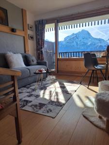 莱德萨阿尔卑斯STUDIO 2 ALPES STYLE CHALET au PIED DE TELESIEGE DU DIABLE的带沙发的客厅,享有山景