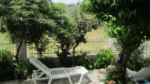毕达哥利翁Sandalis Hotel的花园里种有树木和鲜花的白色长凳