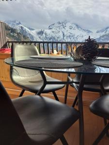 莱德萨阿尔卑斯STUDIO 2 ALPES STYLE CHALET au PIED DE TELESIEGE DU DIABLE的雪覆盖的山景阳台上的玻璃桌子和椅子