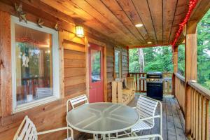 Coffman CoveForested Coffman Cove Cabin with Wood-Burning Stove!的小屋的门廊配有桌椅