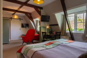 霍恩Hotel De Koegelwieck Terschelling的一间卧室配有一张大床和一张红色椅子