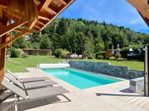 普兰凡Gîte Chalet avec bain nordique et piscine 11 pers Hautes Vosges的庭院内一个带两把躺椅的游泳池