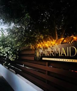 曼德里尔Mermaid Holiday Apartments的木凳上读美人鱼的标志
