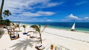 乌罗阿Dream of Zanzibar Resort & Spa - Premium All Inclusive的海滩上设有椅子和帆船