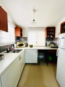 海法КВАРТИРА ВОЗЛЕ МОРЯ!的厨房配有白色橱柜、水槽和冰箱。
