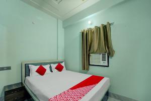 巴特那OYO Flagship Hotel R P Royal的一间卧室配有一张带红色枕头的床和一扇窗户