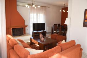 特里卡拉VILLAGE HOUSE的客厅配有橙色沙发和电视