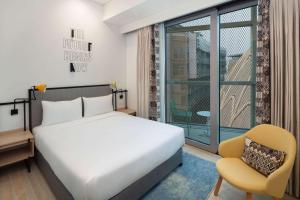 迪拜Rove Expo City的卧室配有床、椅子和窗户。