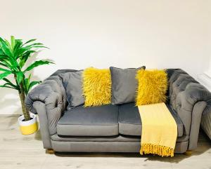 达特福德Beautiful, Luxurious 3 Bed house, Perfect for Contractors , Family & Friends的客厅里一张带黄色枕头的灰色沙发