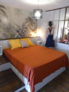 帕皮提Studio Poe Rava的一间卧室配有一张橙色大床,后面有一位女士