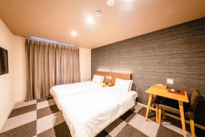 京都HOTEL THE POINT Kiyomizu Gojo的酒店客房设有两张床和一张桌子。