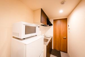 京都HOTEL THE POINT Kiyomizu Gojo的小厨房配有冰箱上方的微波炉