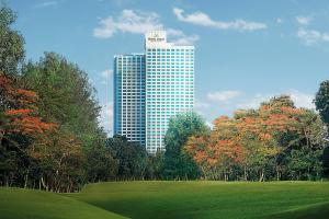 雅加达Hotel Mulia Senayan, Jakarta的一座高大的建筑,有田野和树木