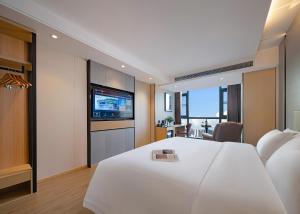 张家界Zhangjiajie Hero Boutique Hotel的酒店客房设有白色的床和电视。