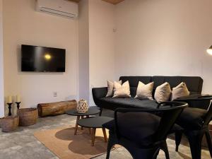 拉佩德雷拉Nandina, en el bosque y playa的客厅配有黑色沙发和电视