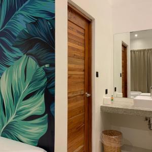 卢纳将军城Bahandi Hotel的浴室设有一扇带热带叶壁画的门