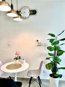 马六甲Melaka AmberCove Homely Seaview 2R2B的一间设有桌子、时钟和植物的房间