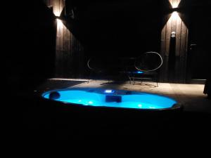 PaplatelėBRENDIS -'Virš Ąžuolų' - Forest SPA - FREE jacuzzi的暗室里的一个蓝色浴缸,配有椅子