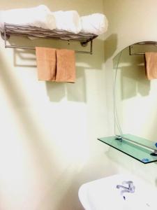 碧瑶Brenthill Condominium的浴室设有水槽和带毛巾的架子。