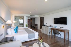 芭东海滩Phuket Karon Emerald Isle Hotel的一间卧室配有一张床、一张书桌和一台电视