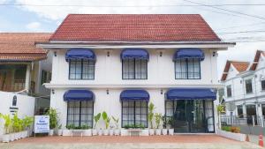 琅勃拉邦Midnight Blue Guesthouse的白色的房子,设有蓝色的窗户和红色的屋顶