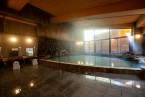 草津亀之井酒店草津YUBATAKE(Kamenoi Hotel Kusatsu Yubatake)的一座带窗户的大型游泳池
