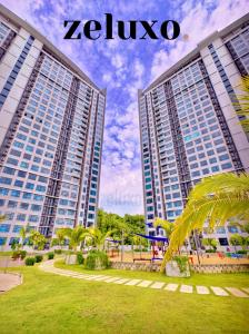 哥打京那巴鲁#1 Jesselton Quay City Pads Seaview by Zeluxo的两座高大的建筑,在一座棕榈树公园里