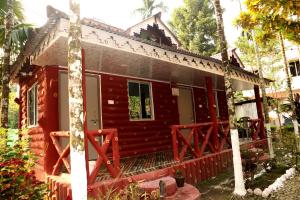 JalpāiguriAyush Jungle Resort的前面有红墙的房子