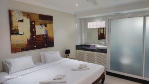 芭东海滩暹罗棕榈酒店的一间带白色大床的卧室和一间浴室