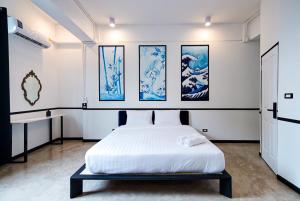 Khlong SanThe Character Yaowarat的卧室配有一张床,墙上挂有绘画作品