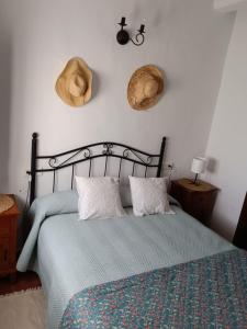 赫纳尔瓜西尔Casa Harillo-Charming 1 bedroom in Genal mountains的卧室配有一张挂在墙上的两顶帽子的床