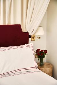 伦敦Magda Boutique Rooms的一张白色的床,上面有红色的床头板和花瓶