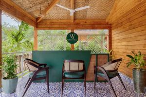 莫尔吉姆Aralea Beach Resort By Stone Wood, Morjim的天井配有三把椅子和一张带标志的桌子