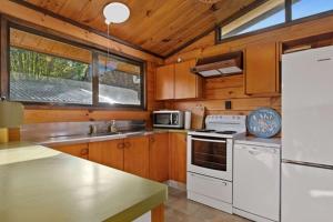 HamuranaLake Haven - Lake Edge的厨房配有白色家电和木制橱柜