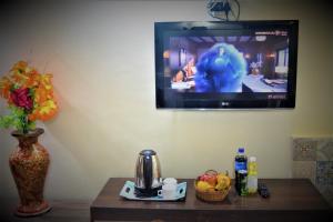 斯利那加Hotel Star of Kashmir的挂在墙上的电视,桌子和桌子