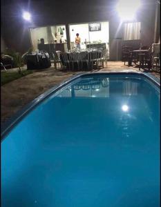 阿西斯Área de lazer Simões的夜间蓝色游泳池,配有桌椅