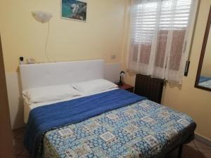 洛阿诺HOTEL GIORDANA的一间卧室配有一张带蓝色毯子的床和窗户。