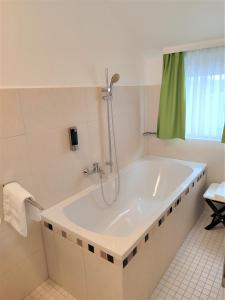 Oberhonnefeld-GierendA3酒店的浴室设有带淋浴的白色浴缸。