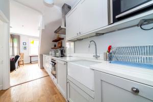 泰晤士河畔金斯顿Stylish 3 BDR apartment wfree parking and garden的厨房配有白色橱柜和水槽