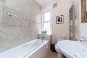 泰晤士河畔金斯顿Stylish 3 BDR apartment wfree parking and garden的白色的浴室设有浴缸和水槽。