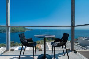 帕诺尔莫斯斯科派洛斯Adrina Grand Hotel的俯瞰大海的阳台配有两把椅子和一张桌子